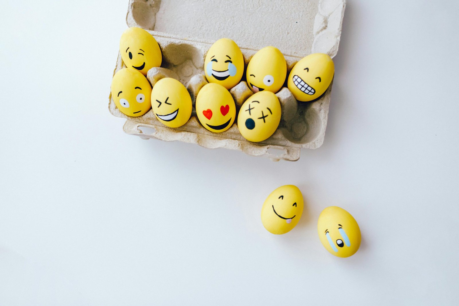 40 Funny Life Quotes That Say “Relax… Nobody Really Has It All Together” Colorful yellow Easter eggs decorated with emoji faces in a carton, adding a fun and creative touch to the holiday.